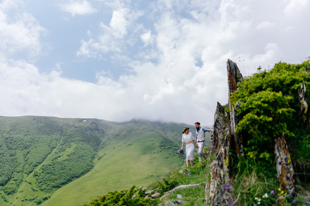 young couple in love, enjoying their trip in the mountains. Side view with large beautiful mountains in the foregroundの写真素材