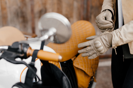 Motorcycle kaferacers. Girl dress leather gloves. Beige leather gloves. Gloves for motorcycle riding. Brown bike seat.の写真素材