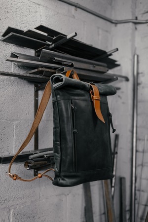 Exclusive black leather backpack. Backpack near the wall. The tools in the garage. Metal pipes near the wallの写真素材