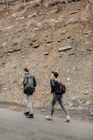 the couple are traveling. Boy and girl with backpacks travel. The couple is on the road. The girl looks up. Girl goes for a man. Travelの写真素材