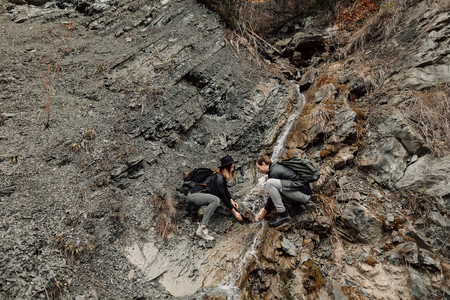 The couple are traveling. Boy and girl with backpacks travel. a couple near the Creek. A man washes his face with water from the Creek. Travelの写真素材