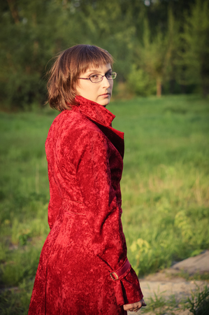 Portrait of a young beautiful woman in a red velvet coat outdoors.の写真素材