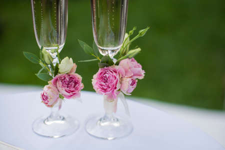 Decorations of pink roses on wedding glasses for the bride and groom. Small wedding bouquets.の写真素材