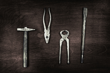 still life of construction tools (hammer, pliers, tongs, drill bit) on a dark wooden Board, close-upの写真素材