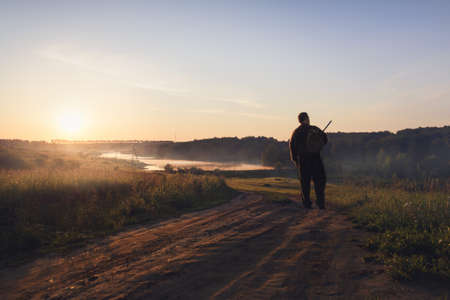 a man walks illuminated by the morning sun on the way to the forest, close up