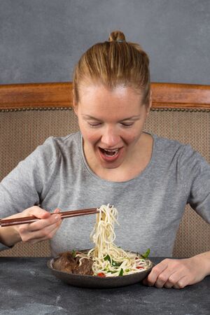 A lady eating beef noodles