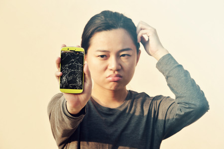Worried woman Holding Broken Screen Smartphoneの写真素材