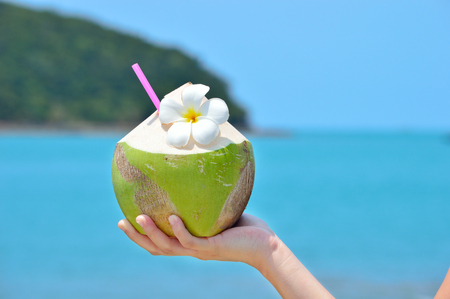 Women holding Tropical green coconut  with exotic flowers and drinking straw.の写真素材