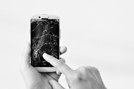 Black and white Hands showing broken smartphone with crashed screenの写真素材
