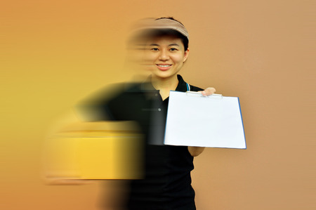 Delivery woman in a rush delivering service with cardboard boxes and clipboardの写真素材