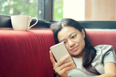Woman using smartphone on couch , focus at handの写真素材