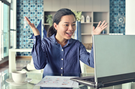Successful business woman with arms up at the office.の写真素材