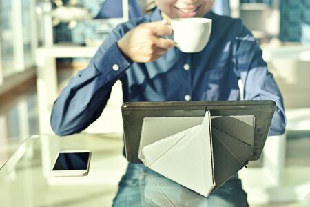 Happy young woman working on tablet while sitting at his working place in officeの写真素材