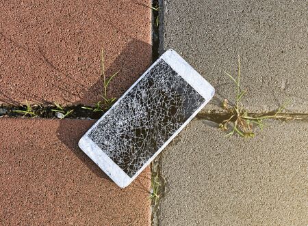Close up of broken mobile phone drop on stone paved sidewalk outdoorsの写真素材