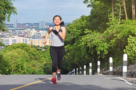 Young asian woman jogging in park smiling happy running and enjoying a healthy outdoor lifestyle.の写真素材