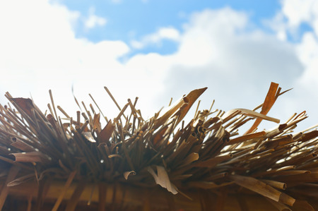 A thatched roof with a blue sky in the backgroundの写真素材