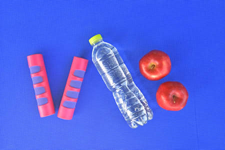 Fruits with dumbells and water bottle on Blue yoga mat
