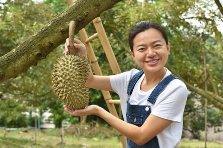 Asian woman farmer holding Durian is a king of fruit in Thailandの写真素材