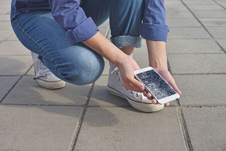 Person holding Broken Smart Phone with a cracked screenの写真素材
