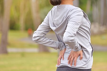 Young asian woman feel pain on her back after jogging work out.の写真素材