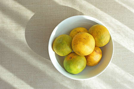 Bowl of orange fruit on fabricの写真素材