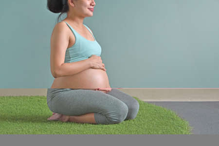 Healthy pregnant woman sitting on the grassの写真素材