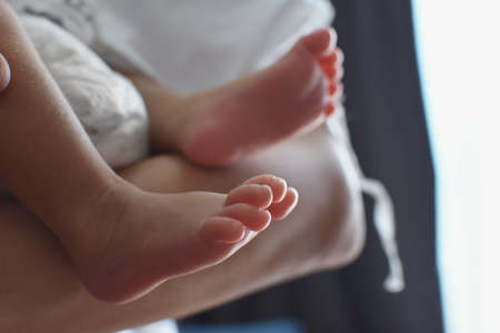 A baby's little feet in her mother's arms.の写真素材
