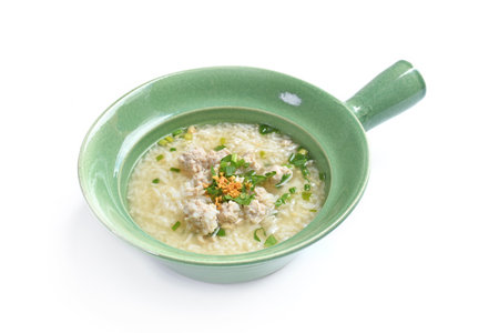 Boiled rice with pork on a bowl. Coriander vegetable leaf on the top of rice soup. It is a famous breakfast in Thailand.の写真素材