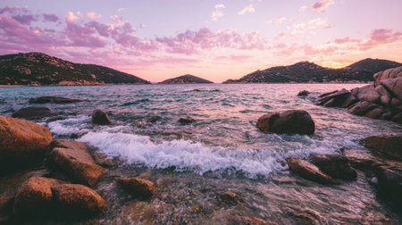 Beautiful rocky coastline with waves gently washing over stones under sunset skyの素材