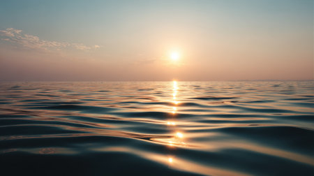Beautiful sunrise over calm ocean with golden light reflecting on gentle waves under clear skyの素材