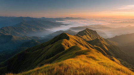 Morning fog lifting from mountain ridge under golden sunlight and blue skyの素材