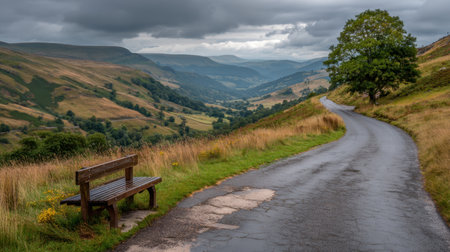 Roadside landscape showing empty bench overlooking winding road through hillsの素材