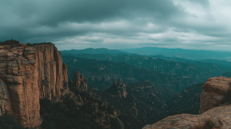 Rocky plateau overlooking vast mountain ranges under heavy overcast skyの素材