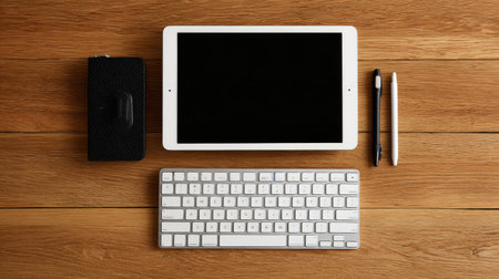 A modern workspace scene showcasing a tablet, keyboard, notebook, and writing instruments on a wooden table, ideal for creative and professional settings.の素材