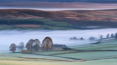 Morning mist lifting over countryside wind farm creating a surreal glowの素材