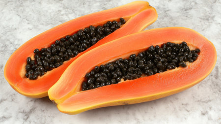 Juicy and vibrant papaya halves reveal black seeds nestled within bright orange flesh, ideal for showcasing healthy eating, tropical flavors, and culinary creativity.の素材
