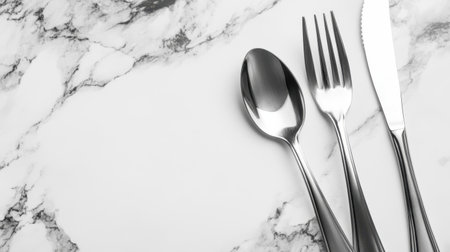 A stylish display of stainless steel cutlery arranged neatly on a beautiful white marble background. Ideal for modern dining, culinary themes, and food-related visuals.の素材