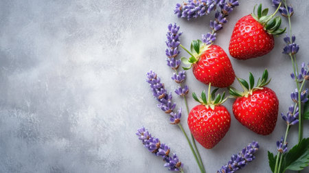 A stunning arrangement of fresh strawberries and fragrant lavender sprigs against a soft gray background, showcasing vibrant colors and natural textures ideal for culinary inspiration.の素材