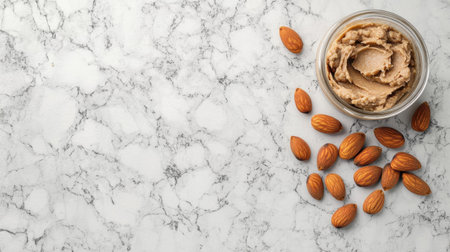 A visually appealing scene featuring creamy almond spread in a glass jar accompanied by scattered raw almonds on a marble countertop, perfect for health-conscious choices.の素材