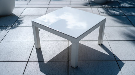 A minimalist white table stands alone on a sunlit outdoor patio, casting soft shadows. This serene setting captures modern design and tranquility, perfect for relaxation.の素材