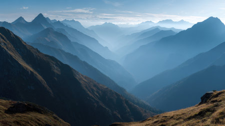 Discover a tranquil mountain landscape featuring layers of mist and soft light that enhance the majestic peaks during the golden hour of a clear day.の素材