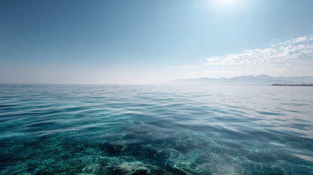 This image captures a serene ocean view with gentle waves under a clear blue sky, showcasing tranquil waters and distant mountains on the horizon.の素材