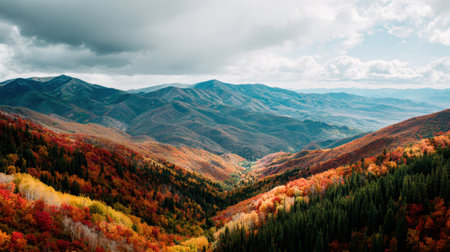 Experience a breathtaking autumn landscape showcasing vibrant fall colors in trees, majestic mountains, and a serene valley under a clouded sky. Perfect for nature lovers.の素材