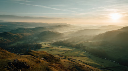 Beautiful landscape featuring rolling hills and a misty valley at sunrise. The soft golden light creates a serene atmosphere over the peaceful countryside.の素材