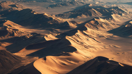 Breathtaking aerial view of a vast desert landscape showcasing golden sand dunes and rolling hills under a clear blue sky. Perfect for capturing natural beauty.の素材