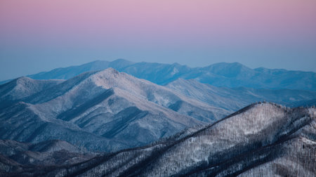 This stunning mountain landscape captures the tranquility of snow-covered peaks during dusk, showcasing a beautiful gradient of pink and blue in the sky.の素材