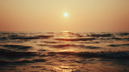 Experience the breathtaking beauty of a tranquil sunset over gentle ocean waves, with warm sunlight reflecting off the water, creating a serene atmosphere.の素材