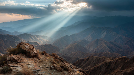 Capture the beauty of a majestic mountain range as sunlight breaks through clouds, illuminating rugged terrain and creating a serene atmosphere for nature lovers.の素材