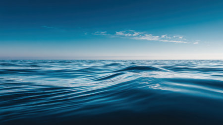 A serene view of calm ocean waves captures the beauty of nature with soft reflections under a clear blue sky, creating a perfect scene for relaxation and peace.の素材