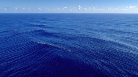 Serene image of deep blue ocean waves under a clear sky, showcasing gentle clouds floating above, perfect for evoking feelings of peace and tranquility in any setting.の素材